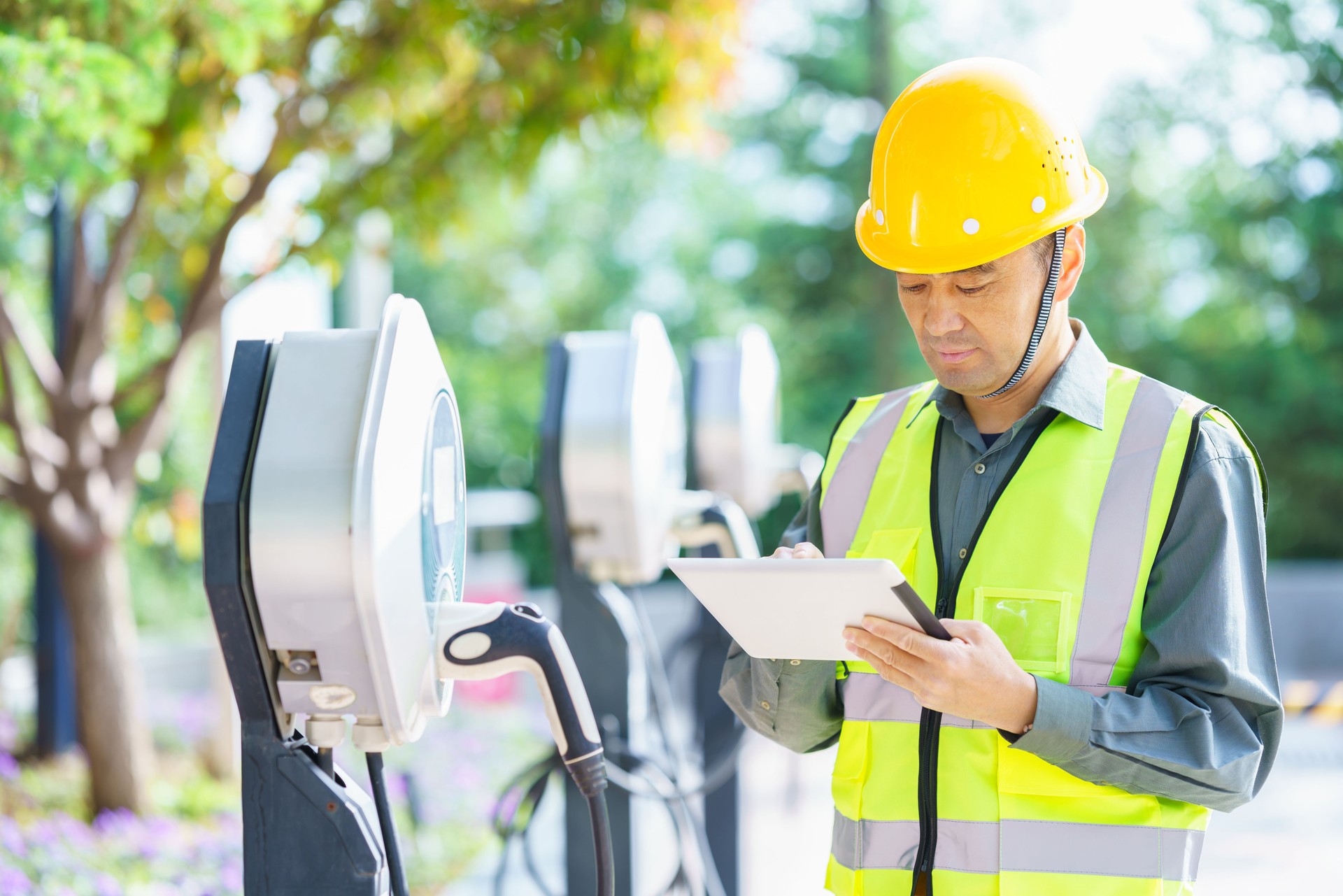 Asian middle-aged electrical technician working at electric vehicle charging station